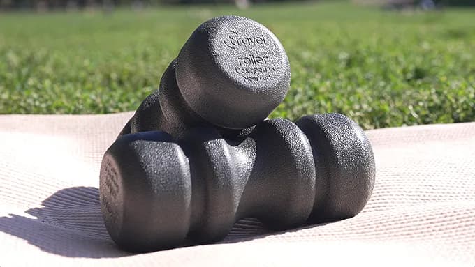 Two Travel Rollers resting on a mat outdoors, showing the molded surface and the engraved end