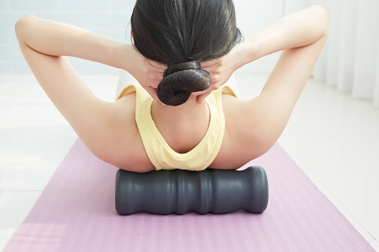 Someone lying on a mat with the PU95 under the upper back, hands behind the head